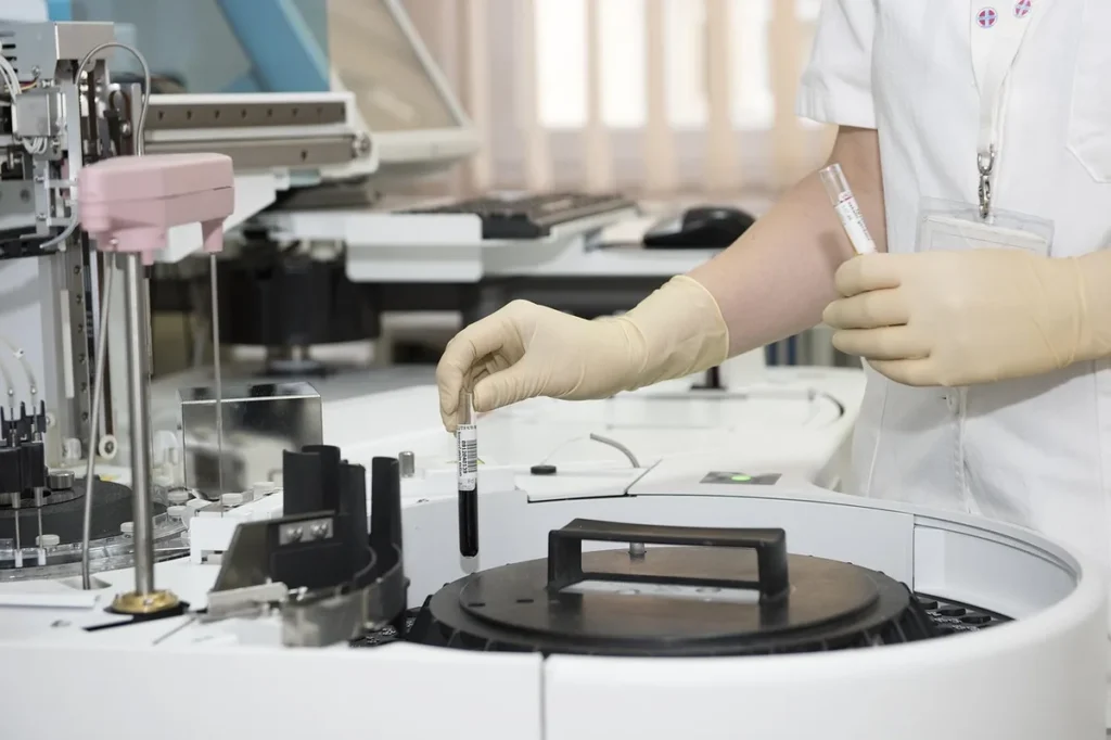 Laborant z próbką krwi przy analizatorze: cholesterol i glukoza na czczo w badaniach